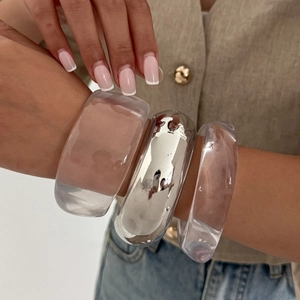 Chunky clear acrylic and shiny silver metal bangles styled in a stacked set