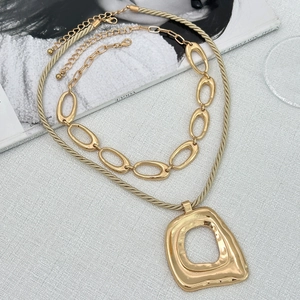 Collana a strati dorata con pendente a croce e perle finte su una rivista di moda
