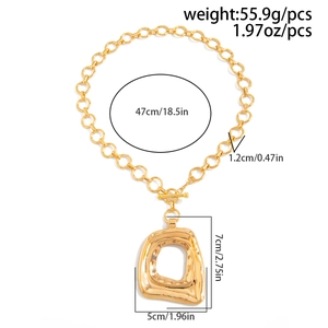 Dettaglio di una collana a catena dorata con grande pendente martellato e chiusura a T