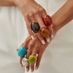 Close-up of hand wearing colorful irregular resin rings in bold geometric styles