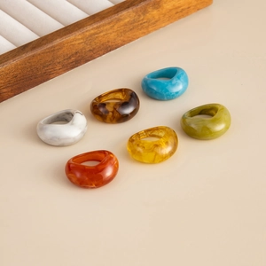 Detailed flat lay of six colorful resin rings in marble, amber, and green tones