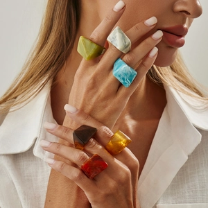Set of six geometric resin rings in vibrant marble and solid colors on a model's hand