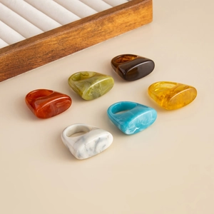 Set of six irregular acrylic resin rings in various colors on a wooden tray display