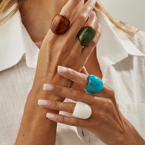 Close-up of colorful irregular resin rings in amber and green worn on a finger