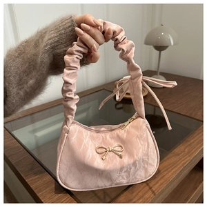 Detailed view of pink pleated handbag featuring gold bow hardware and ruffled top handle