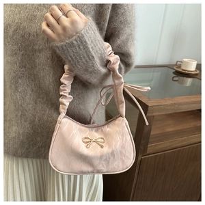 Detailed view of pink bow handbag with pleated texture and golden hardware