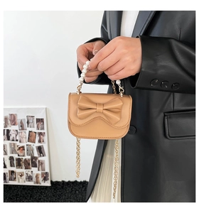 Dettaglio della mini borsa color cuoio con fiocco grande e manico in perle sintetiche