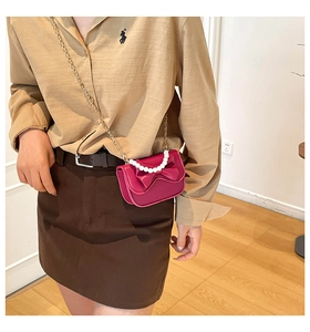 Dettaglio mini borsa a tracolla rosa scuro con grande fiocco e manico in perle chic