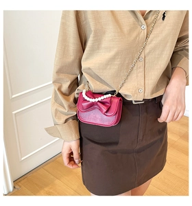 Detail of rose pink mini bag with 3D bow and pearl handle on gold chain strap