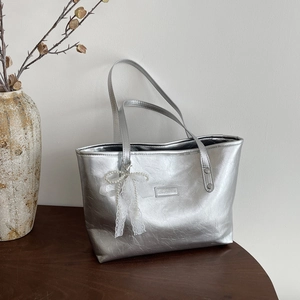Borsa tote argento metallizzato con fiocco di pizzo e perle su tavolo vintage