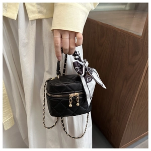 Dettaglio mini borsa trapuntata nera con tracolla a catena e foulard in seta sul manico