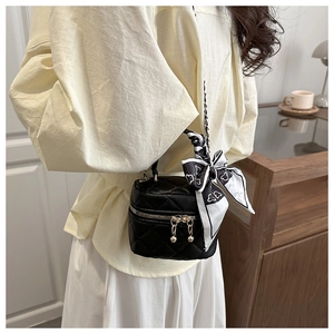 Dettaglio mini borsa trapuntata nera con cerniere dorate e manico decorato con foulard