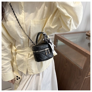 Dettaglio di mini borsa trapuntata nera con cerniera a perla e foulard sulla maniglia