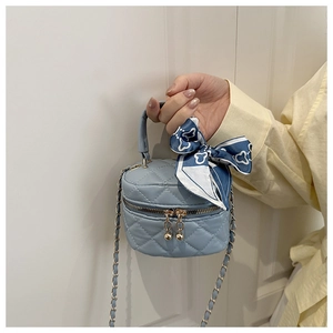 Dettaglio della mini borsa trapuntata con catena dorata e foulard decorativo