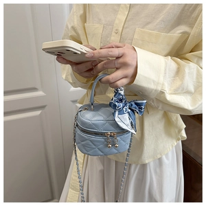 Dettaglio mini borsa trapuntata azzurra con catena dorata e sciarpa di seta decorativa