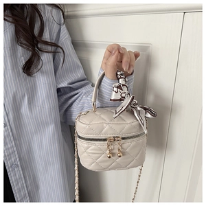 Dettaglio della mini borsa matelassé crema con foulard di seta avvolto sul manico