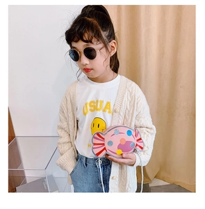 Fillette portant un mini sac bandoulière rose en forme de bonbon avec pois colorés