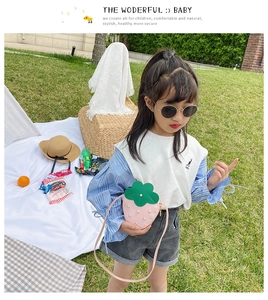 Cute strawberry-shaped kids crossbody bag with pearl studs worn by a girl outdoors