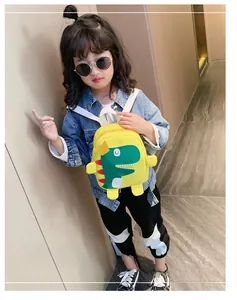 Zainetto giallo per bambini con motivo di dinosauro verde indossato da bambina