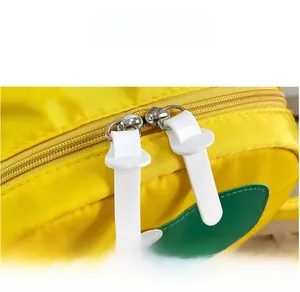 Dettaglio dello zaino in nylon giallo con doppia cerniera in silicone bianco e decori verdi