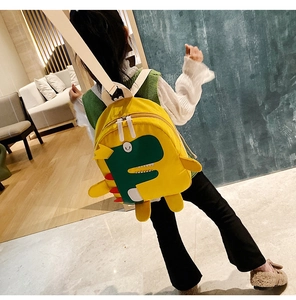 Dettaglio dello zaino giallo per bambini con dinosauro verde e lettera F bianca