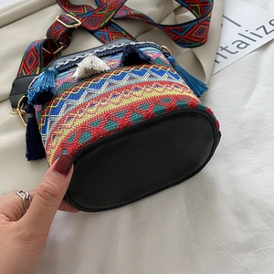 Dettaglio della borsa a secchiello bohémien con nappe colorate e ampia tracolla géo