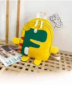 Dettaglio di uno zaino giallo per bambini con un dinosauro verde dei cartoni e nylon