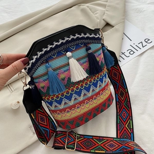 Dettaglio della borsa a secchiello boho intrecciata con motivi etnici e nappe colorate