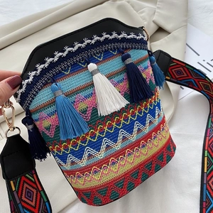 Dettaglio borsa a secchiello boho con ricami colorati, nappe e tracolla intrecciata