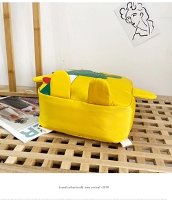 Dettaglio di uno zaino a forma di coccodrillo giallo su un supporto a griglia in legno