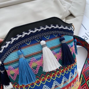 Dettaglio della borsa a secchiello etnica intrecciata con nappe colorate e tracolla ricamata