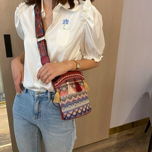 Dettaglio della borsa a secchiello etnica intrecciata con nappa boho e tracolla a motivi