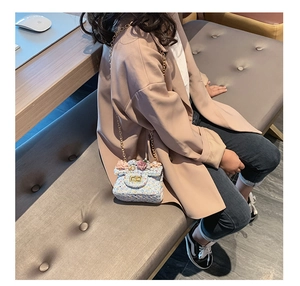 Dettaglio borsa a tracolla in tweed azzurro con fiori 3D e chiusura rotante dorata