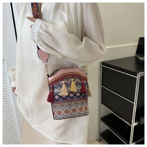 Dettaglio della borsa a secchiello etnica con trama geometrica, nappe e tracolla larga