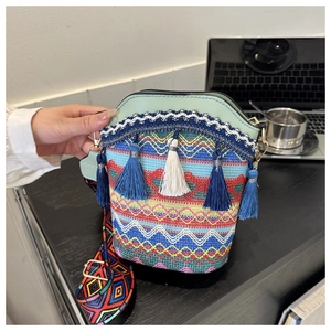 Dettaglio della borsa a secchiello tessuta colorata con nappe decorative e tracolla jacquard