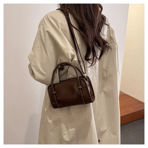 Side view of model wearing dark brown crossbody bag with unique knot detail