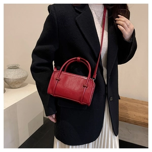 Detail view of red leather square bag with FASHION embossing and chic cylindrical handle