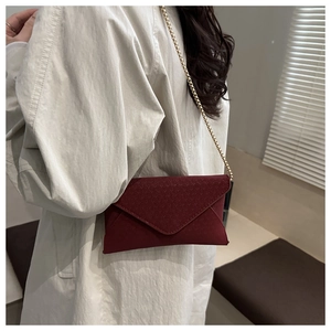 Detailed view of burgundy envelope bag with geometric texture and gold chain strap