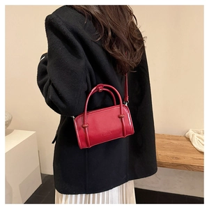 Detail of red glossy patent leather handbag with embossed fashion lettering and shoulder strap