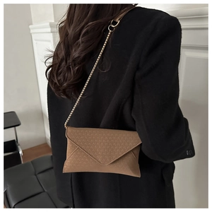 Close-up of brown envelope crossbody bag with geometric texture and gold chain strap