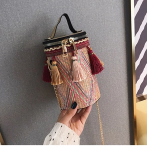 Dettaglio della borsa a secchiello in paglia boho con frange colorate e tracolla a catena