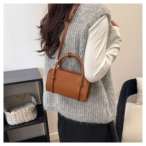 Rear view of brown leather crossbody bag with Fashion embossing worn by a model