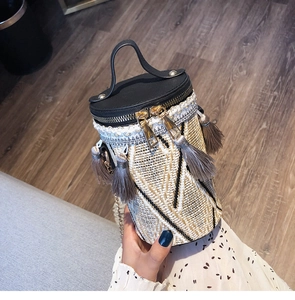 Dettaglio di borsa a secchiello tessuta boho con motivi geometrici e nappa decorativa