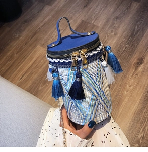 Dettaglio di una borsa a cilindro intrecciata con frange etniche e perle decorative