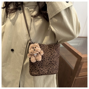 Dettaglio borsa a secchiello leopardata in camoscio con ciondolo a cane e tracolla in pelle