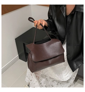 Detail of dark brown tote bag with premium lychee grain leather and sleek handle