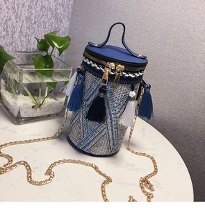 Dettaglio della borsa a secchiello bohémien in paglia con nappe blu e catena d'oro