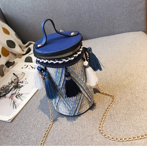 Dettaglio della borsa cilindrica intrecciata blu con frange etniche, nappe e catena