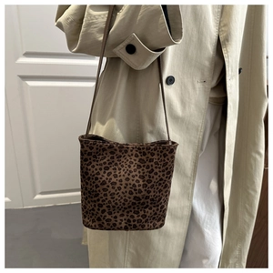 Dettaglio borsa a secchiello leopardata con tracolla in pelle su cappotto beige