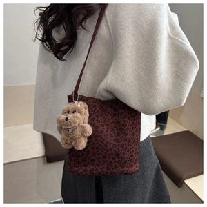 Dettaglio borsa a secchiello leopardata rosso scuro con ciondolo di peluche e tracolla